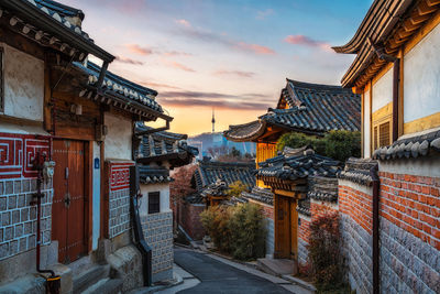 Street amidst buildings in city against sky during sunset