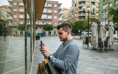 Young man using smart phone on street