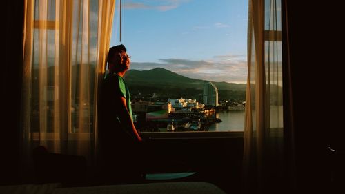 Rear view of woman looking through window