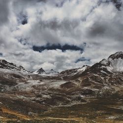 Scenic view of snow covered mountains against cloudy sky