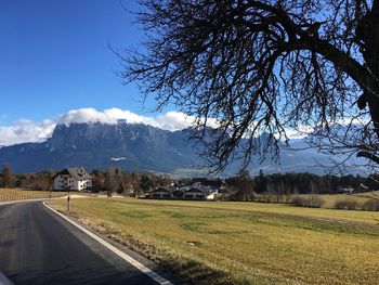 Road amidst field and mountains against sky