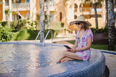 Side view of woman sitting on mobile phone