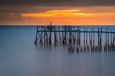 Pier on sea against sky during sunset