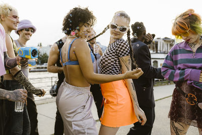 Carefree non-binary friends dancing in party on promenade in city