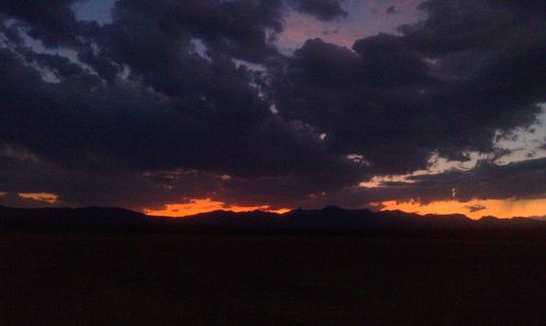 Scenic view of dramatic sky over silhouette landscape