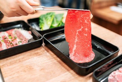 Hand picks a premium rare slices of kagoshima wagyu a5 beef with marbled texture.