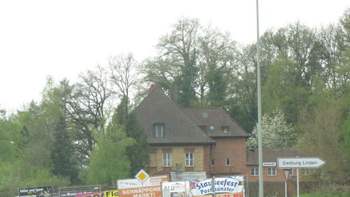 Information sign by trees against sky