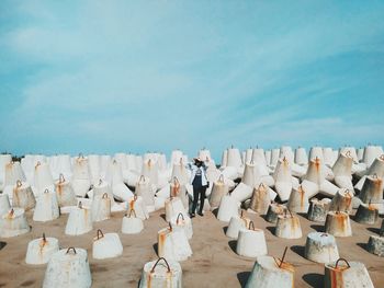 Woman standing at amidst stones at beach against sky