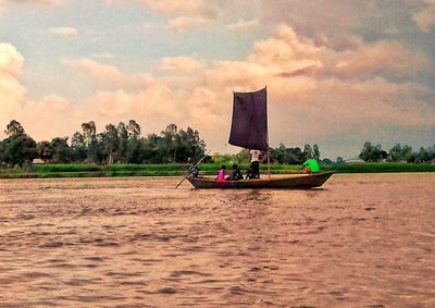 People on boat against sky during sunset