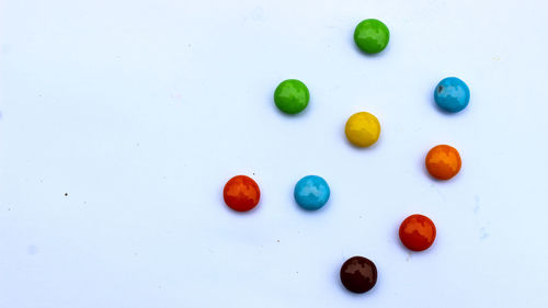 High angle view of multi colored candies against white background