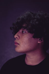 Close-up portrait of young man against black background