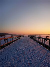 Pier on sea against clear sky at sunset