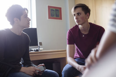 Teenager looking at friend sitting in brightly lit bedroom