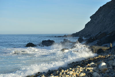 Pacific ocean wave splashing against rocks below a rocky cliff face in baja california sur, mexico
