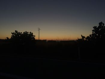 Silhouette trees on landscape against clear sky