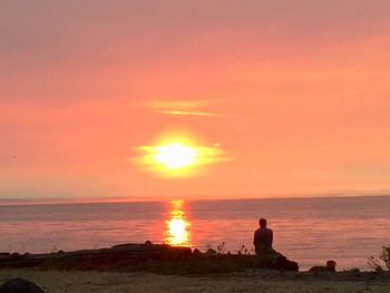 Silhouette man on beach against orange sky