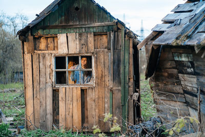 Girl looks out the window from an old wooden house, nature in the country