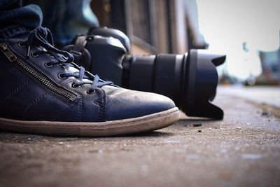 Low section of man wearing shoes by camera on sidewalk