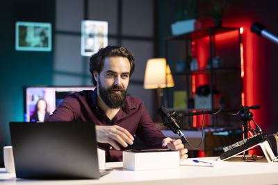 Portrait of man using laptop at desk in office