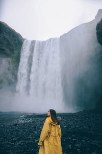 Rear view of woman standing against waterfall