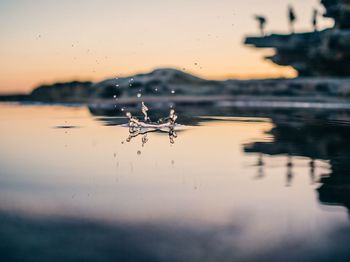 Surface level view of drop falling into lake at dusk