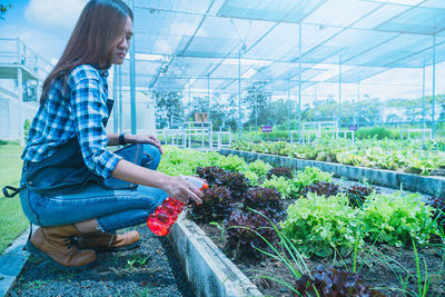 Side view of woman standing in greenhouse