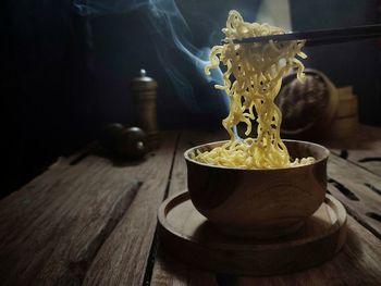 A bowl of hot boiled noodles is ready to eat in a wooden table. dark mood photography concept