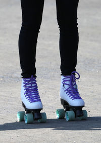 Low section of woman roller skating on footpath