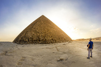 Rear view of senior man standing against pyramid against sky