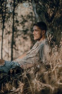 Side view of a young man sitting in the forest