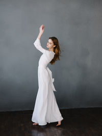 Woman with arms raised standing against wall