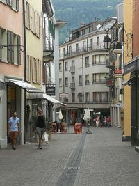 People walking on street amidst buildings in city