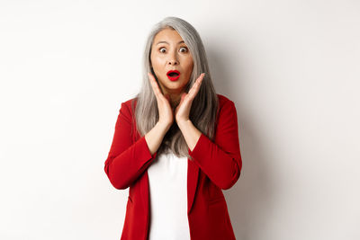 Portrait of young woman standing against white background