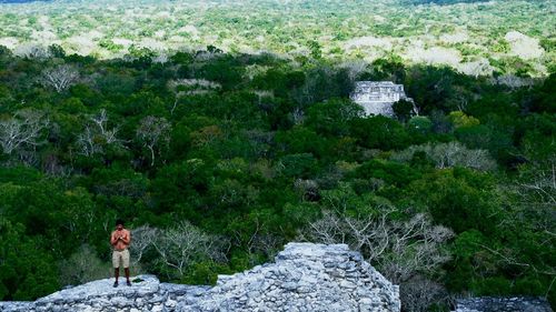 Man standing on rock against trees