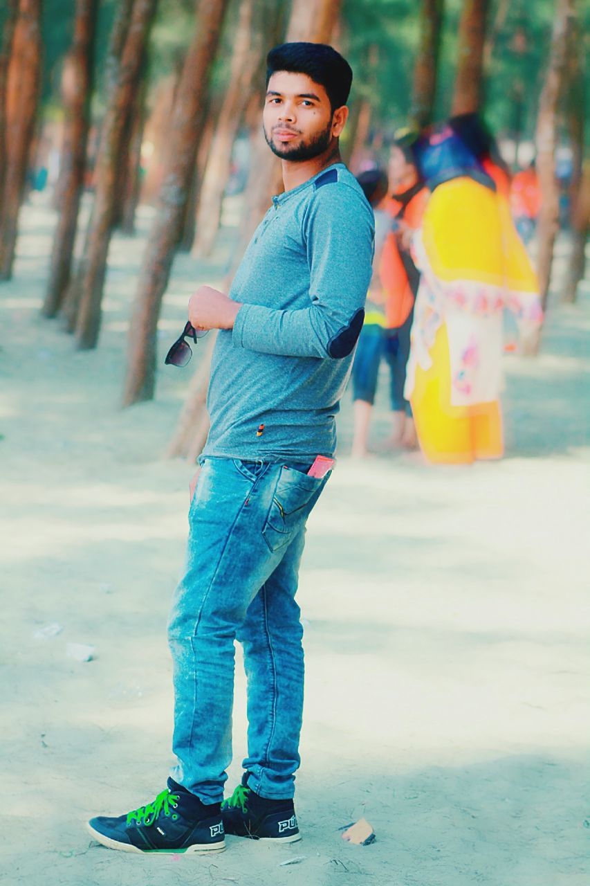 full length, one person, looking at camera, casual clothing, real people, focus on foreground, portrait, day, standing, young adult, leisure activity, lifestyles, clothing, young men, incidental people, land, side view, outdoors, jeans