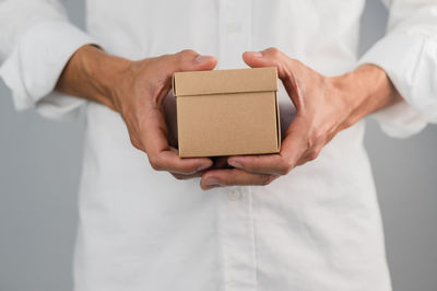 Midsection of man holding mobile phone in box