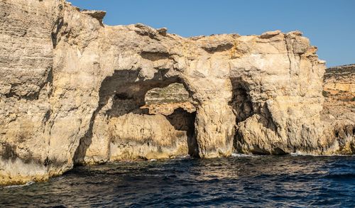 Rock formations in sea against sky