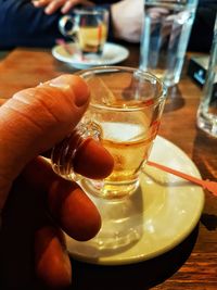 Close-up of hand holding drink on table