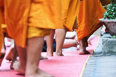 Low section of monks walking on red carpet