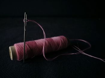 Close-up of thread spool with needle against black background