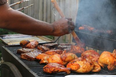 Close-up of man preparing food on barbecue grill