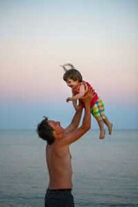 Father and son standing on beach against clear sky