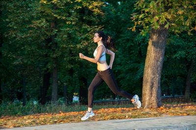 Full length of woman running on plant against trees