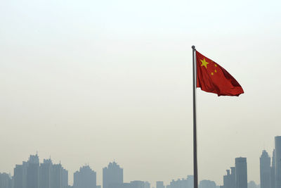 Chinese flag in city against clear sky