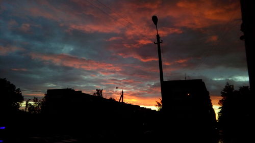 Silhouette of buildings against cloudy sky at sunset