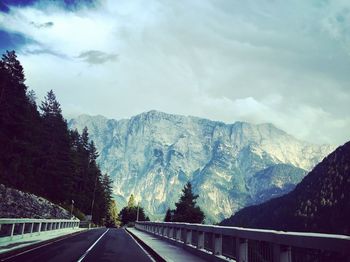 Road by mountains against sky