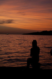 Silhouette people looking at sea against sky during sunset