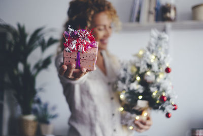 Woman holding christmas decoration on table at home