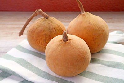 Three of fresh ripe santol fruits or wild mangosteen on striped kitchen linen