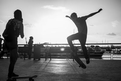 People jumping by sea against sky